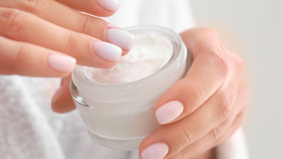 Nahaufnahme von Händen, die eine Creme auftragen.